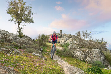 Wall Mural - active senior woman cycling with her electric mountain bike in the rough landscape of National Parc Serra de São Mamede near Marvao in central Portugal, Europe
