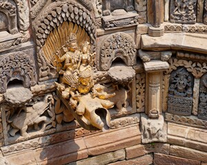 Wall Mural - Intricate stone carvings and a golden statue at an ancient temple in Nepal