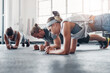 © peopleimages.com - Group, fitness class and exercise with push ups on floor for arm strength, healthy body and wellness. Training collaboration, people and muscle challenge in gym for weightloss and physical activity