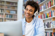 © Home-stock - Cheerful Black student man in wireless headphones looking at laptop and smiling, talking on video call from college library