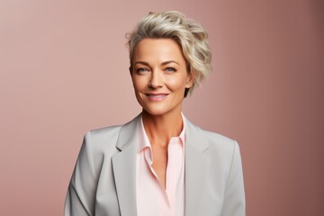 Canvas Print - Portrait of a smiling woman in her 50s wearing a professional suit jacket on pastel or soft colors background