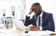 © Prostock-studio - Exhausted young african american entrepreneur working with laptop in office, touching his forehead, copy space