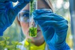 © Dina - lab scientist worker holding a glass test tube with green algae seaweed