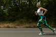 © Atlas - Strong athletic woman in sportswear with headphones runs along road in park