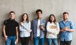 © Prostock-studio - College students with books smiling to camera over grey wall, having break