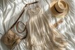 © Fotograf - A woman's clothing and accessories laid out on a bed, including a dress, hat, sunglasses, and purse