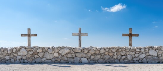 Poster - row of different sized and styled stone crosses on top of a white wall against a clear blue sky. Creative banner. Copyspace image