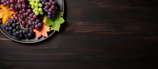 Wall Mural - top view of various types of grapes on vintage plate on black wooden surface. Creative banner. Copyspace image