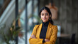 © NaphakStudio - Professional Indian female manager in a black turtleneck stands confidently in a modern office, reflecting professionalism and stylish leadership.