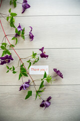 Poster - branch of blooming purple clematis, on a light wooden table