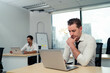 © KANGWANS - A man is sitting at a desk with a laptop open in front of him. He is wearing a black tie and he is in a state of distress
