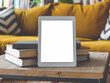 © Llama-World-studio - In the living room, a digital tablet rests beside books on a coffee table near a couch