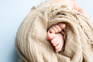 Wall Mural - small feet of a newborn on a blue background. soft focus