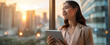 © Natali - Happy confident young businesswoman professional holding smart tablet looking out office window onto cityscape view. Ambitious & driver female entrepreneur visualising & manifesting dreams & goals