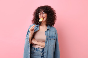 Wall Mural - Beautiful woman with lollipop on pink background