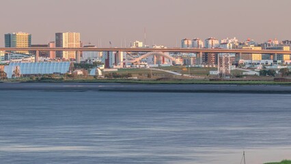 Wall Mural - Park Tejo and river timelapse in Lisbon with park of Nations district modern architecture on a background, Portugal. View with Vasco da Gama Bridge from walking route Percurso Ribeirinho de Loures