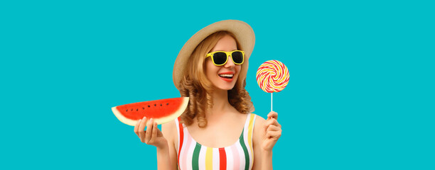 Wall Mural - Summer portrait of happy young woman with lollipop watermelon wearing straw hat on blue background