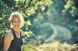 © Mikel - A woman with blonde hair is smiling in a forest.