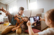 © Vorda Berge - Father playing with son while being photographed by daughter at home