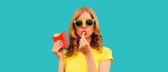 Wall Mural - Portrait of stylish young woman eating french fries, fried potatoes fast food