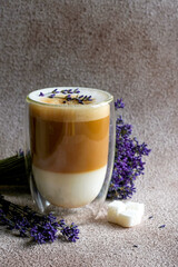 Wall Mural - coffee cup with latte art on a concrete background. Hot latte in big double wall glasses with lavender. Lavender latte. Lavender Raf Coffee . Soft focus. Place for text. Copy