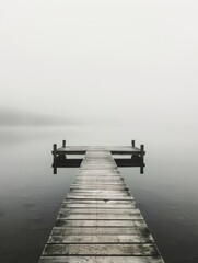 Wall Mural - A wooden pier is in the water with a foggy sky above