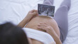 © tampatra - A portrait of happy Asian pregnant woman in bedroom at home with baby ultrasound. Having a baby. Family people lifestyle. Mom love.