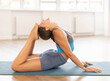 © JackF - Plastic girl training cobra position on blue mat in yoga studio with wide windows