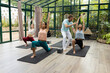 © Wavebreak Media - A diverse group of people at yoga class and instructors practice yoga in a glass house