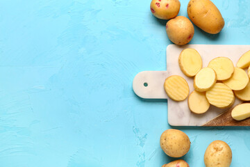 Wall Mural - Board with slices of fresh raw potatoes on blue background