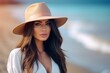 © Juan Hernandez - A woman with long brown hair and a tan hat is standing on a beach