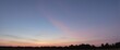 © Qbertstudio - A tranquil evening with a serene sunset painting the sky in pink and blue hues, silhouetting the distant tree line and creating a peaceful landscape