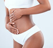 © Maass/peopleimages.com - Hands, underwear and stomach of woman in studio for health, wellness or weight loss on white background. Fitness, gut and female model with slim body for diet, balance or digestion with closeup