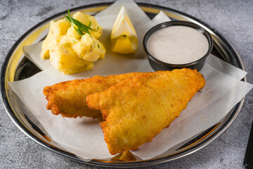 Wall Mural - Deep fried coated fish fillet with potato salad on stone table