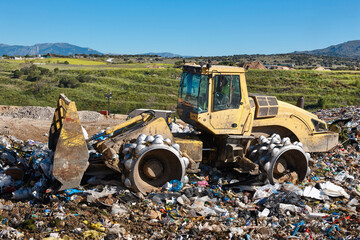 Wall Mural - Heavy machinery shredding garbage in an open air landfill. Pollution