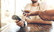 © JorSons/peopleimages.com - Hands, pos and phone at a cafe for payment, ecommerce or coffee shop waiter tip for customer service. Smartphone, scanner and person at a restaurant with app for paperless, bill or digital currency