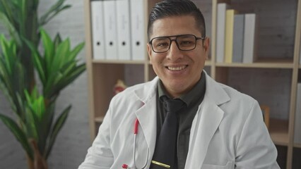 Sticker - A smiling hispanic man in a white coat with a stethoscope, posing in a clinic office setting