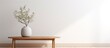 © Ilgun - Minimalistic living room interior featuring a wooden table and a round vase with decorative sprigs against a white wall creating a stylish ambiance with copy space image