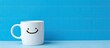 © Ilgun - A white mug featuring a smiley face drawing against a blue backdrop with ample copy space image