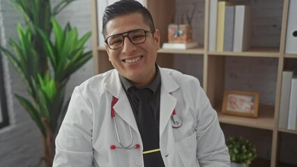 Canvas Print - Young hispanic man in doctor's uniform, a positive, confident, and happy smile in the clinic