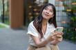 © Phimwilai - Modern smiling woman uses her phone to play online. Check finances via online banking Talk through the application Online communication, business ideas, learning.