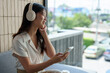 © Phimwilai - Happy Asian woman listening to music on mobile phone while sitting on sofa at coffee shop Relaxed smiling young woman with headphones in the morning Holiday relaxation concept.