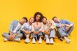 © Prostock-studio - Five multiracial friends are sitting on a yellow background and taking a nap together. They are all wearing casual clothing and have their heads resting on each others shoulders.