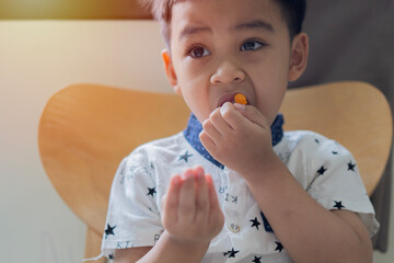 Portrait image of small Asian child, boy 3 years old wants to eat gelatinous sweets.