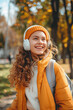 © Emanuel - Happy young woman enjoying music through wireless headphones while walking outside