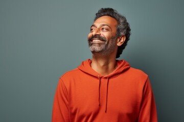 Portrait of a blissful indian man in his 40s dressed in a comfy fleece pullover in solid color backdrop