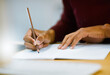 © Hira/peopleimages.com - Writing, notebook and hands of person in library for university education, scholarship course or project research. Growth, studying and college student with notes, pencil and planning for exam.