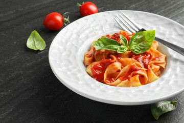 Wall Mural - Delicious pasta with tomato sauce and basil on dark textured table, closeup