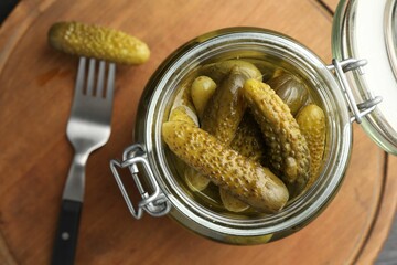 Wall Mural - Pickled cucumbers in jar and fork on wooden table, top view