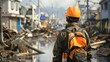 © Zamans - tech in disaster management a man in a black jacket and orange helmet stands in front of a white building, carrying a black and orange backpack, while a white and blue sign stands nearby